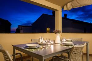 a table with plates and bowls on a balcony at night at Apartments Lea in Mandre