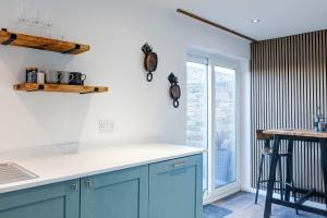 a kitchen with blue cabinets and a window at Estuary Point - unique sea views in Amble