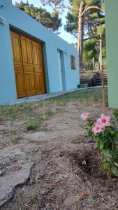 un edificio con una puerta y flores delante en Plácida, en Villa Gesell