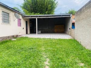 an open garage with a grassy yard next to a building at Casa Completa para Hospedagem in Rosário do Sul