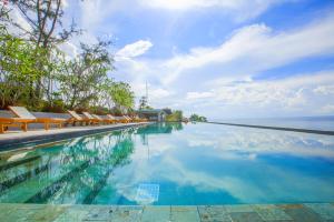 uma piscina com cadeiras e o oceano em Norn Talay Surin Beach Phuket em Praia de Surin