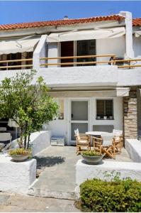 a house with a table and chairs in front of it at Agistri House Pefkohori in Pefkochori