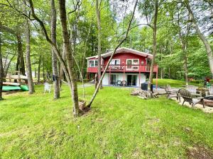 una casa roja en medio de un parque en Peaceful Pocono Lakefront, beach, pools, firepit, pets, en Arrowhead Lake