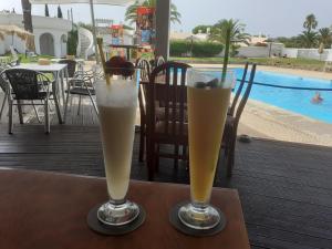 two glasses of drinks sitting on a table near a pool at Villa Blue - Aldeia do Golfe in Quarteira