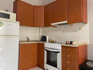 a kitchen with wooden cabinets and a white stove top oven at Διαμέρισμα με θέα σε πάρκο! in Serres