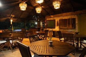 a restaurant with wooden tables and chairs and lights at Canto Leela - Bangalôs pé na areia in Serra Grande