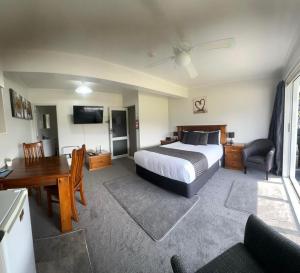 a bedroom with a bed and a desk and a table at Coromandel Seaview Motel in Coromandel Town