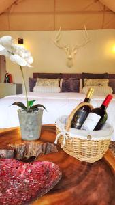 DariénGlamping Bellavista - Escapada Romántica en el Lago Calima的一张桌子,上面放有瓶装葡萄酒和一篮鲜花