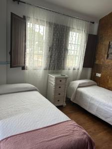 una camera con due letti, un comò e una finestra di Apartamentos Gerena 5 B primero a Gerena
