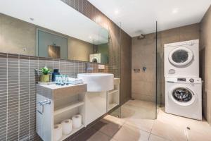 a bathroom with a sink and a washing machine at Stunning City Views from Modern 1BR Apartment King in Darwin