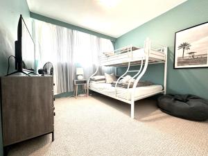 a bedroom with two bunk beds and a television at 3 bedrooms with Views over Kirra! in Gold Coast