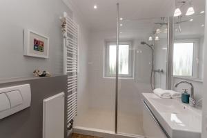 a white bathroom with a shower and a sink at LITZKOW 11101 in Morsum +5 photos