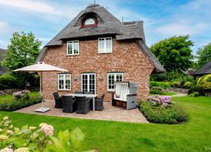 a house with a thatched roof with a patio at LITZKOW 12802 in Morsum