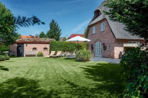 a brick house with an umbrella and a grass yard at LITZKOW 15808 in Morsum