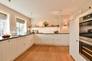 una cucina con mobili bianchi e pavimento in legno di LITZKOW 16402 ad Archsum