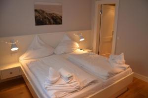 un letto con lenzuola e cuscini bianchi e uno specchio di LITZKOW 16402 ad Archsum