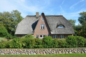 una casa con tetto di paglia e muro di pietra di LITZKOW 16402 ad Archsum