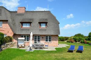 una casa con tetto di paglia e sedie di LITZKOW 16203 ad Archsum