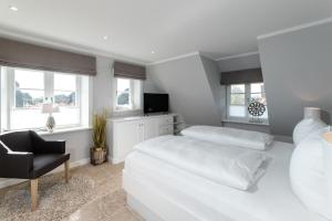 una camera bianca con due letti e una sedia di LITZKOW 16205 ad Archsum