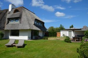 a thatch roofed house with two benches in a yard at LITZKOW 19201 in Keitum