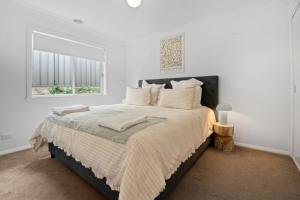 a white bedroom with a large bed with a window at Mountain Vista Retreat - Comfort Meets Style in Lake Albert