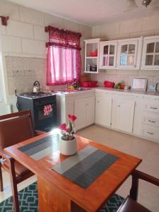 a kitchen with a wooden table and a kitchen with white cabinets at Love Den in Christ Church +4 photos