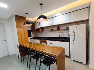 a kitchen with a wooden table and a refrigerator at Apto em frente a piscina no centro de Pelotas in Pelotas