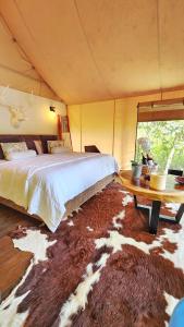 DariénGlamping Bellavista - Escapada Romántica en el Lago Calima的卧室配有一张大床和一张桌子,铺在地毯上