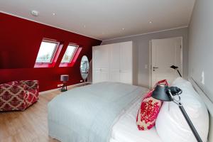 una camera da letto con pareti rosse e un letto con una lampada di LITZKOW 16103 ad Archsum