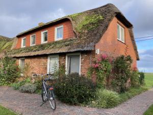a bike parked in front of a brick house with a grass roof at Opas Hus auf Pellworm in Pellworm +9 photos