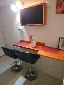 einen Schreibtisch mit 2 Stühlen und einen TV an der Wand in der Unterkunft Love Den in Christchurch