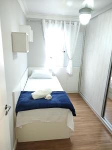 une chambre avec un lit avec une couverture bleue et une fenêtre dans l'établissement Apartamento Expo Center Norte a 900 metros, à São Paulo