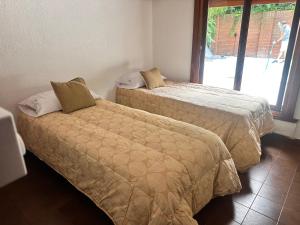 Dos camas en una habitación con ventana. en Cuidamos tu casa, en Villa Gesell