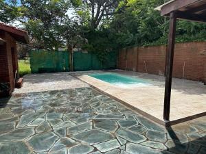 un patio trasero con piscina y una valla de ladrillo en Cuidamos tu casa, en Villa Gesell