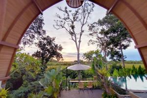 an outdoor patio with an umbrella and a pool at Ubud 3-bedrooms with sunset view in Ubud