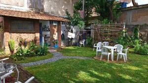 - un jardin avec des tables et des chaises blanches dans la cour dans l'établissement Casa em meio a natureza - Ideal para casal, à Rio de Janeiro