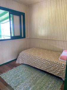 a bedroom with a bed in the corner of a room at Casa dos Girassóis na Lagoa in Araranguá