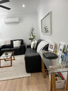 a living room with a black couch and a glass table at Annie's Apartment in Mount Gambier