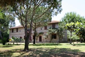 una vecchia casa in pietra con alberi di fronte di Settebello Village a Lido Di Fondi