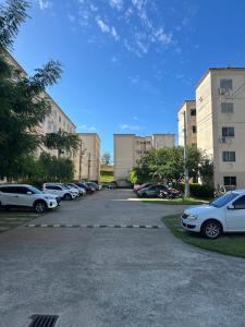 a parking lot with cars parked in front of buildings at Apartamento da Letícia in Camaçari