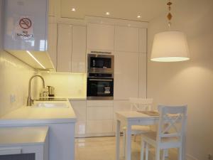 een keuken met witte kasten en een tafel en stoelen bij Grand-Tourist Old Town Center Apartments in Gdańsk