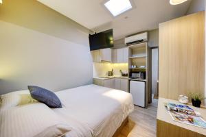 a small bedroom with a bed and a kitchen at Hmlet Essentials Kallang in Singapore
