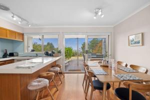 cocina con mesa, sillas y barra en Surfside Serenity, en Anglesea
