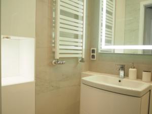 ein weißes Badezimmer mit einem Waschbecken und einem Spiegel in der Unterkunft Grand-Tourist Old Town Center Apartments in Danzig