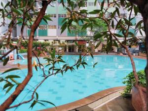 Una gran piscina con árboles frente a un edificio. en The Royale Sentra Tower Kuning Powered by Cocotel, en Yakarta