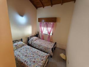 two beds in a room with a window at Chalet Mar de Ajo in Mar de Ajó