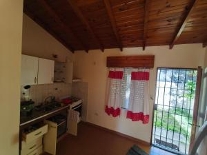 a kitchen with red and white curtains and a window at Chalet Mar de Ajo in Mar de Ajó