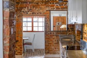 a kitchen with a brick wall and a table at Secret River Cottage in Windsor +44 photos