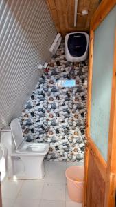 ein Bad mit WC und ein TV an der Wand in der Unterkunft Eva Cabins in Dalhousie