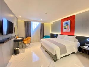a hotel room with a bed and a flat screen tv at Trio Azana Style Kebumen in Kebumen
